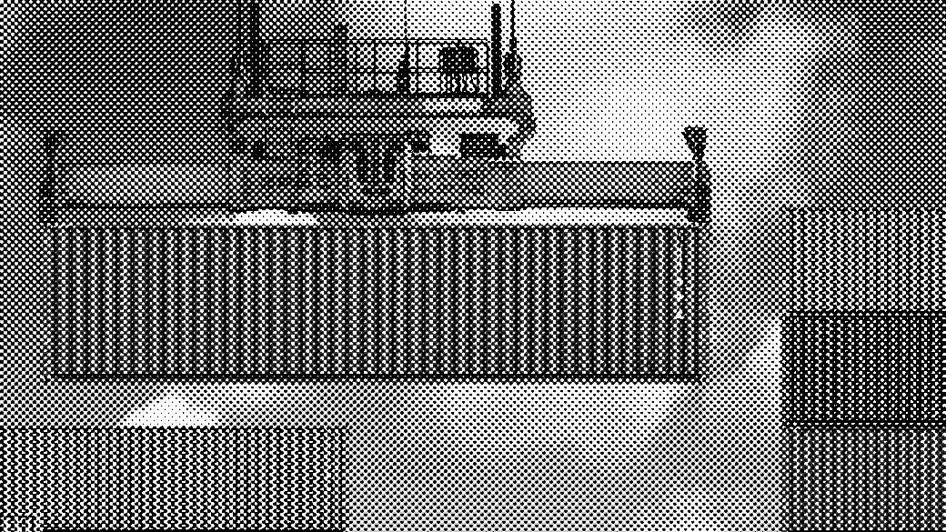 Red shipping container hoisted above others, blue sky with clouds.